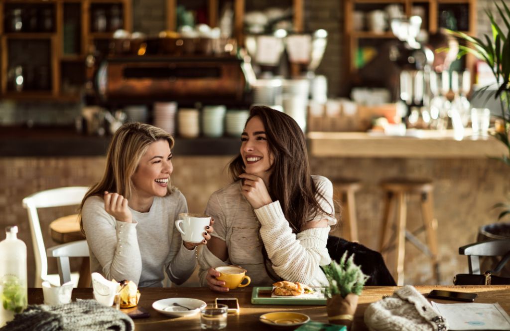 two women talking and celebrating success over a coffee